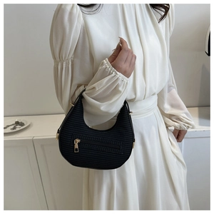 Detail of black crescent shoulder bag with horizontal texture and gold-tone metal zipper