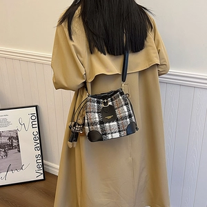 Plaid tweed bucket bag with leather trim and bear charm shown from a back perspective
