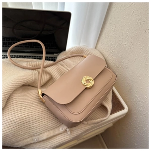 Detail of beige rectangular flap bag with an elegant golden knotted metal buckle close-up