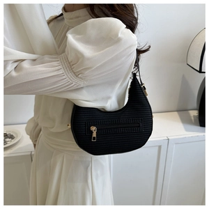Close-up of black knitted crescent hobo bag with gold zipper and textured surface