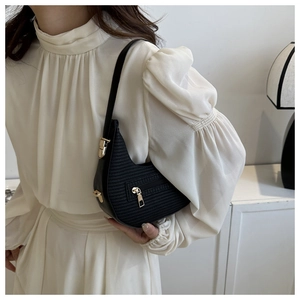 Close-up of black crescent hobo bag with woven texture and gold zipper detail