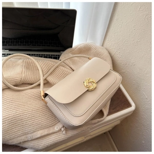 Detail of a creamy white leather shoulder bag featuring a gold spiral twist metal buckle