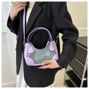 Detail of lavender leather and grey denim patchwork shoulder bag worn by model