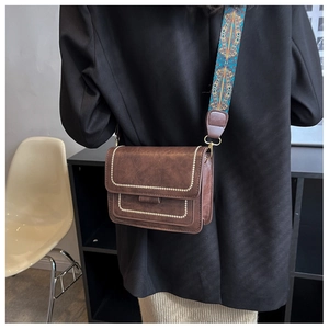 Detail of vintage brown bag with colorful ethnic strap and gold rivet accents