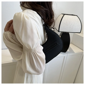 Detail view of black crescent hobo bag with woven texture and gold metal hardware