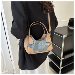 Detail of color-block baguette bag with denim texture and brown leather trim accents