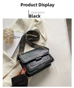 Detail of black vintage leather crossbody bag with ethnic patterned woven shoulder strap