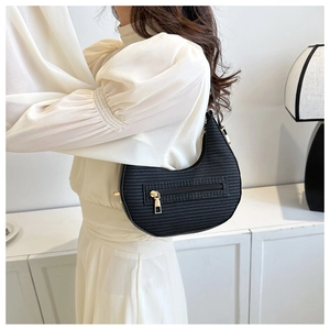 Detail of black woven texture on crescent shoulder bag with golden zipper and hardware