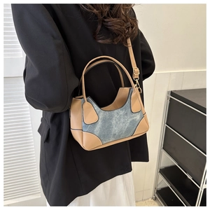 Detail of color-block baguette bag featuring denim texture and brown leather straps