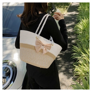 Detail of woven tote bag with ribbon bow and thick cotton rope handles for summer beach