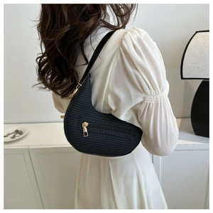Detail of black crescent bag with woven texture and gold zipper worn over the shoulder