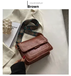 Detail of brown vintage crossbody bag with contrast stitching and ethnic pattern strap