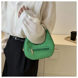 Detail view of a green woven texture hobo bag worn with a white chiffon shirt