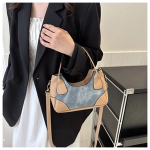 Detail of color-block contrast underarm bag with leather corners and gold hardware