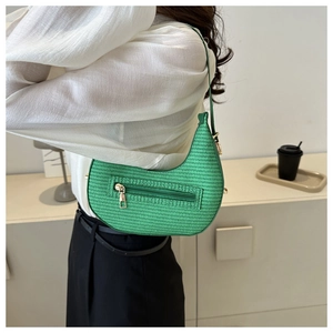 Macro detail of grass green woven crescent bag with golden zipper and textured weave