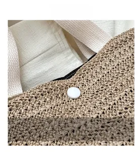Detail of woven straw tote bag featuring natural texture and white fabric strap