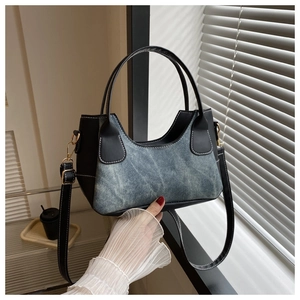 Detail of blue denim and black faux leather bag with contrast white stitching