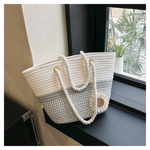 Detail of woven tote bag with blue color blocks, cotton rope handles and daisy charm