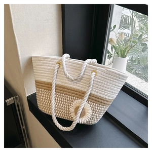 Close-up of woven tote bag with sunflower charm and thick cotton rope handles