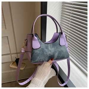 Detail of blue denim and purple leather stitching with golden hardware on handbag