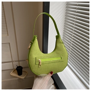 Detail of bright green woven crescent bag with golden metal zipper and smooth leather trim