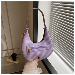 Detail of purple woven crescent bag with front zipper and gold-tone metal hardware