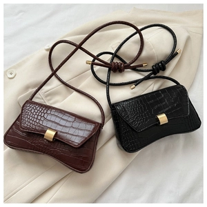 Close-up of crocodile pattern leather texture and gold metal locks on two small square bags