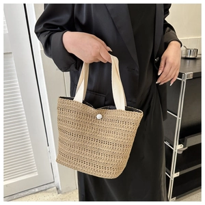 Close-up of natural woven texture and white canvas handles on a beach straw handbag