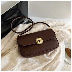 Detail of vintage brown leather handbag with gold twist lock on a beige knit sweater