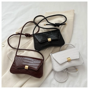 Detailed view of three minimalist crocodile pattern crossbody bags in black, brown, and white