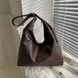 Dark brown large leather Hobo bag on white knitwear with soft window light and shadows