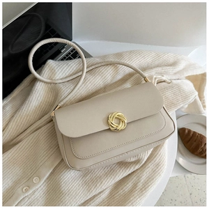 Detail of a beige crossbody bag featuring a signature gold twist lock on soft leather