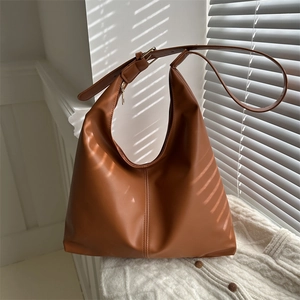 Minimalist caramel brown leather hobo bag with adjustable strap in warm sunlight