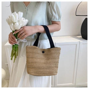 Detail of straw woven tote bag with black ribbon handles and elegant flower bouquet