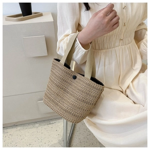 French straw handbag worn by model against warm interior for casual beach vacation style