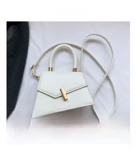 Detail view of the asymmetric trapezoid design and bright gold twist lock on the white bag