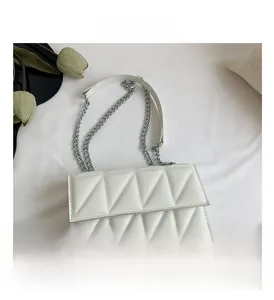 Close-up of white quilted leather flap bag with silver chain strap in a lifestyle setting