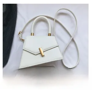 Detailed view of white trapezoid crossbody bag shown next to a smartphone for size reference