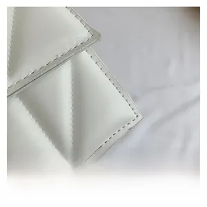 Detailed close-up of white leather texture and fine stitching on a vintage square bag