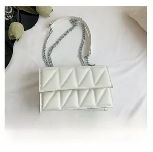 Detailed top view of white quilted crossbody bag with silver chain strap beside a phone