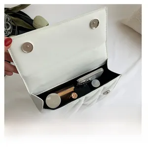 Interior view of white quilted crossbody bag showing storage space for phone and makeup