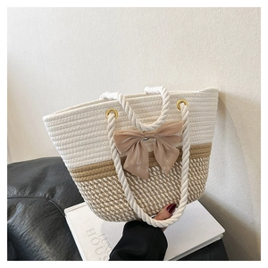 Elegant woven tote bag with contrast colors and silk bow detail on a rope handle