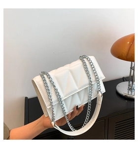 Gros plan d'un sac à bandoulière matelassé blanc avec chaîne argentée et renfort en cuir