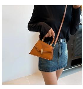 Detail showing the caramel trapezoid leather handbag with a gold metal lock and handle