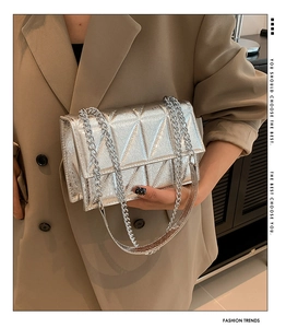Detail of silver quilted crossbody bag with metallic chain strap and cracked texture leather