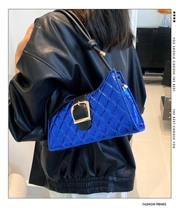 Close-up of electric blue quilted baguette bag with glossy finish and metal buckle