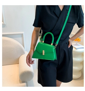 Vibrant green leather trapezoid bag with gold twist lock carried by a model