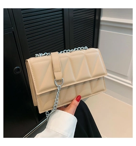 Détail du sac bandoulière matelassé beige avec chaîne argentée et boucle décorative