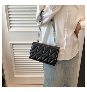 Close-up of black quilted shoulder bag featuring silver chain strap and triangle textures