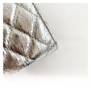 Macro shot of metallic silver quilted fabric with rhombus patterns on a shoulder bag